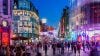 Night-time city street with colored lighting and pedestrians
