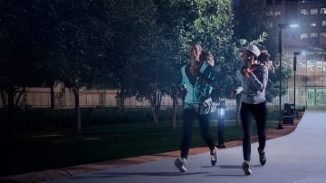 夜间，人们在明亮的公园里慢跑 